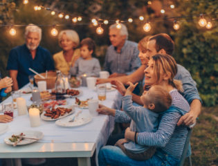Photo of a big family during dinner, celebrating holiday together in the backyard