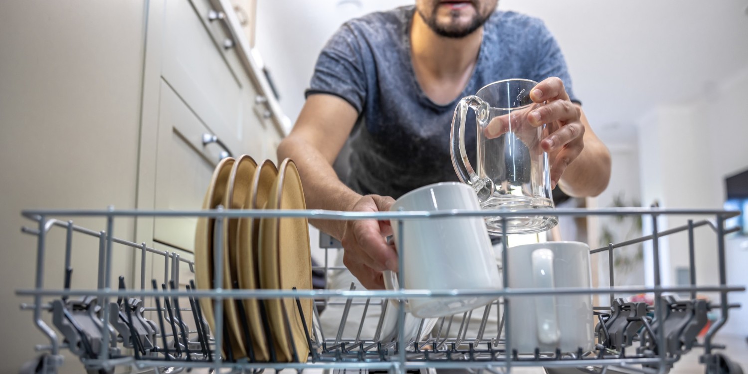 man-front-open-dishwasher-takes-out-puts-down-dishes (1)